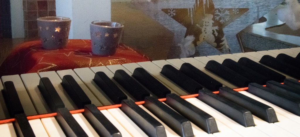 Eine Klaviertastatur, die sich in ihrem Deckel spiegel, mit Kerzen und einem Stern.