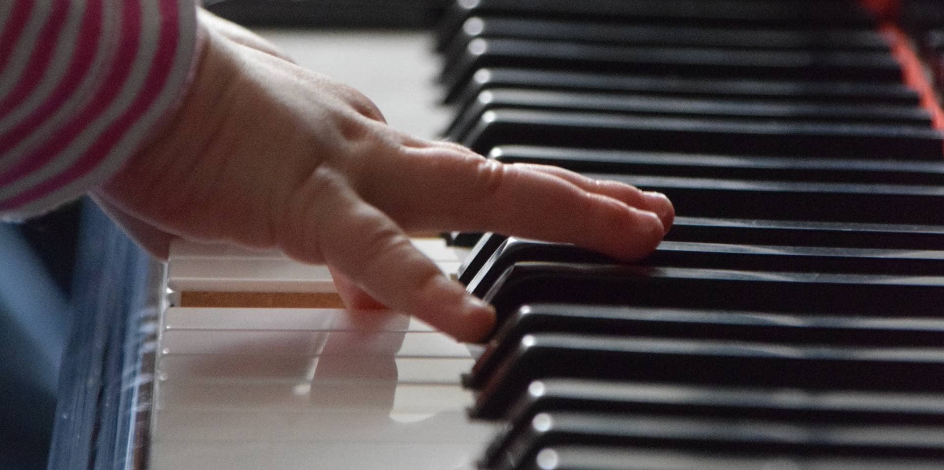 Eine Kinderhand auf den Tasten einen Klaviers