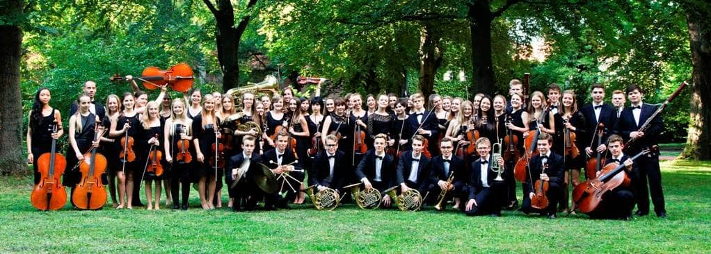 Die Sinfonietta steht als Gruppe in eine Park mit ihren Instrumenten zusammen